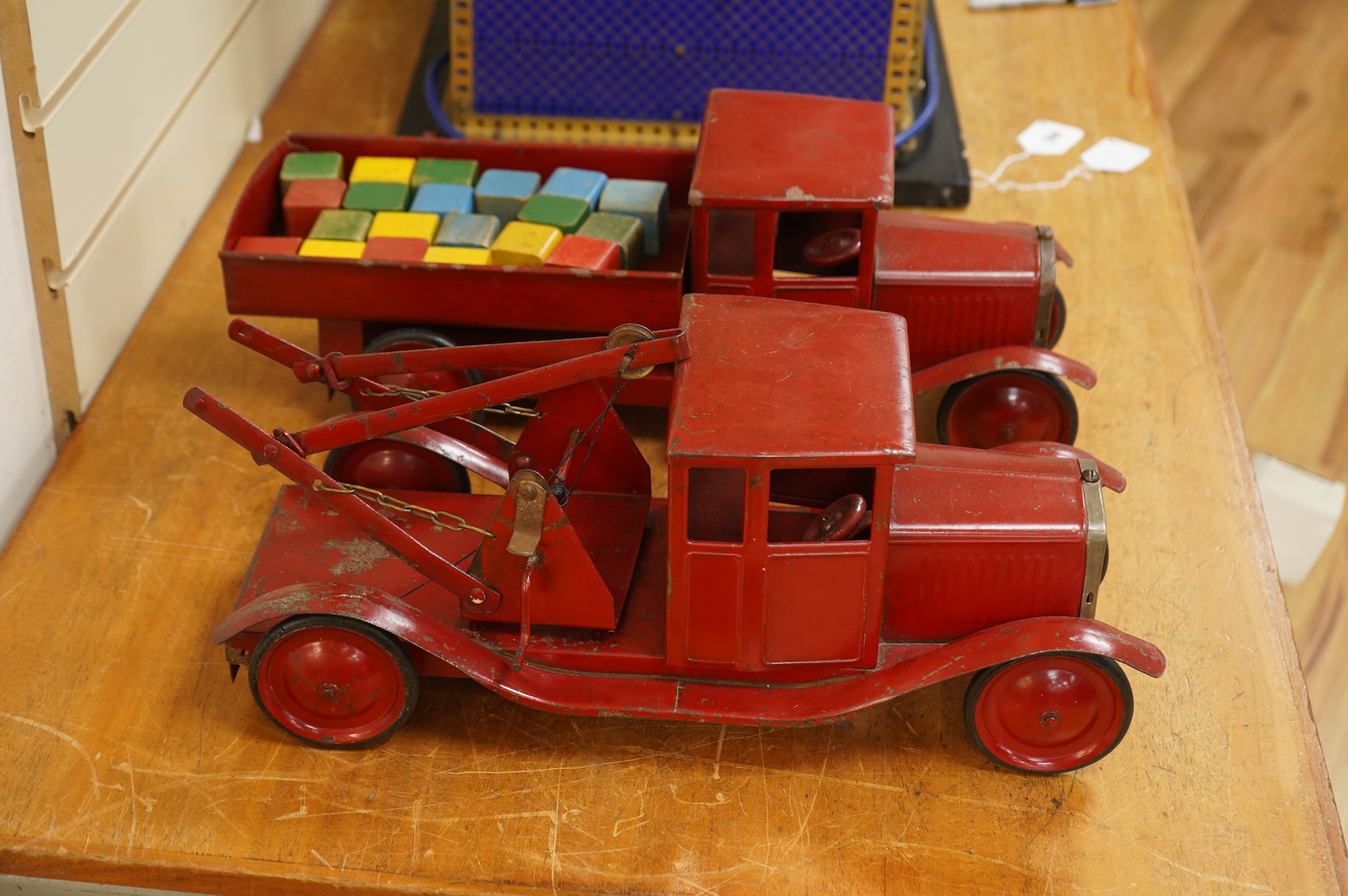 Two 1930's/40's Tri-ang large scale tinplate trucks, both with similar frames and cabs, one as a wreck truck with mounted crane, the other has a wagon with painted wooden blocks, each approximate 44cm long